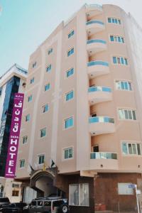 a large building with a purple sign on the side of it at Sara Hotel Apartments in Ajman 