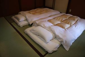 a group of white beds sitting on a floor at Yoshiki no Sato Dainichi no Yado in Hida