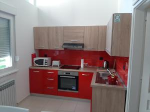 a small kitchen with red cabinets and a microwave at Apartman Kod Kestena in Osijek