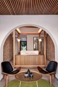 ミコノス・シティにあるMyconian Naia - Preferred Hotels & Resortsのベッド1台、椅子2脚、テーブルが備わる客室です。