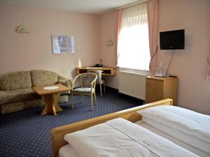 a hotel room with a bed and a couch and a desk at Hotel Ebner in Bad Königshofen im Grabfeld