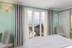 a bedroom with a bed and a large window at Hotel Penzance Harbour View in Penzance