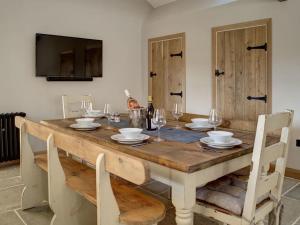 a dining room table with chairs and a television at Dovecote in Chipping Campden