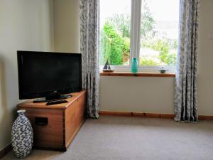 a flat screen tv sitting on a wooden stand in front of a window at Holiday Accommodation Perth Scotland - Oakview in Perth