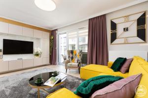 a living room with a yellow couch and a tv at M&M-Spa&Art Bali, Nadmorskie Tarasy in Kołobrzeg