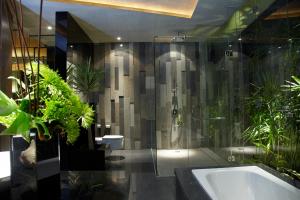 y baño con ducha y bañera con plantas. en iVilla by Ekosistem, en Seminyak