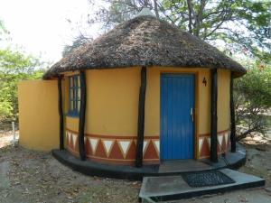 a small hut with a thatched roof and a blue door at Gweta Lodge in Gweta