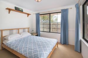 um quarto com uma cama com cortinas azuis e uma janela em Bottlebrush em Quindalup