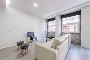 a living room with a white couch and two windows at Oporto Downtown View Apartment in Porto