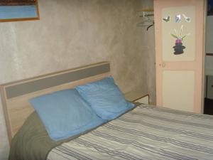 ein Bett mit blauen Kissen in einem Schlafzimmer in der Unterkunft Le Bravard in Jumeaux