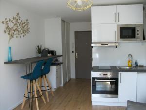 een keuken met witte kasten en blauwe barkrukken bij "Monplaisir", beau studio neuf, classement 2 étoiles in Lyon