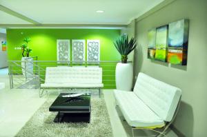 a living room with two white chairs and a green wall at Travelodge in Gaborone