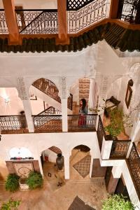 - une vue de tête d'un bâtiment avec une femme debout sur un balcon dans l'établissement Riad Aya, à Marrakech