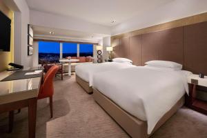 a large hotel room with two beds and a desk at Grand Hyatt Taipei in Taipei