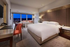 a hotel room with a large white bed and a desk at Grand Hyatt Taipei in Taipei