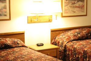 a hotel room with two beds and a phone on a table at Rodeway Inn Gateway to Medora T-Roosevelt & Makoshika State Park in Wibaux