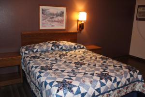 een slaapkamer met een bed met een quilt bij Rodeway Inn Gateway to Medora T-Roosevelt & Makoshika State Park in Wibaux