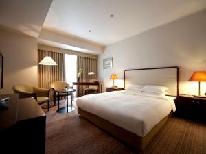 una camera d'albergo con un letto grande e una scrivania di The Cypress Mercure Hotel Nagoya a Nagoya
