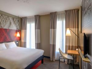 a hotel room with a bed and a desk and a television at ibis Paris Tour Montparnasse 15eme in Paris