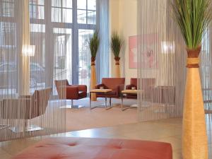 エアフルトにあるメルキュール ホテル エアフルト アルトシュタットの建物内の椅子と植物のあるロビー