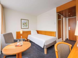 um pequeno quarto de hotel com uma cama e uma mesa em Novotel Freiburg am Konzerthaus em Friburgo em Brisgóvia