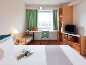 Cette chambre comprend un lit, un bureau et une fenêtre. dans l'établissement Ibis Madrid Alcorcon Tresaguas, à Alcorcón