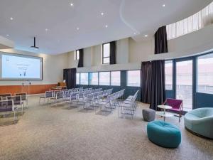 uma sala de conferências com cadeiras e um ecrã de projecção em Novotel Paris 13 Porte d'Italie em Le Kremlin-Bicêtre