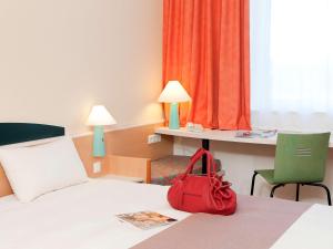 una borsa rossa seduta su un letto in una camera d'albergo di ibis Luxembourg Sud a Livange