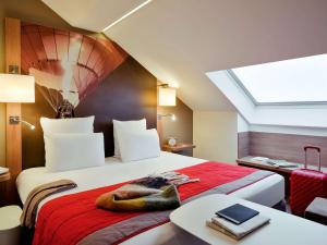 een slaapkamer met een groot bed en een dakraam bij Mercure Vienne Sud Chanas in Chanas