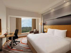 a hotel room with a bed and a desk and a window at Novotel Hyderabad Convention Centre in Hyderabad