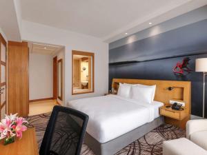 a hotel room with a bed and a chair at Novotel Hyderabad Convention Centre in Hyderabad