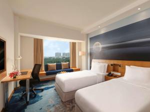 a hotel room with two beds and a desk at Novotel Hyderabad Convention Centre in Hyderabad