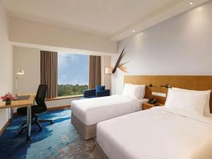 a hotel room with two beds and a desk at Novotel Hyderabad Convention Centre in Hyderabad