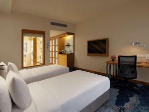 a hotel room with two beds and a desk at Novotel Hyderabad Convention Centre in Hyderabad