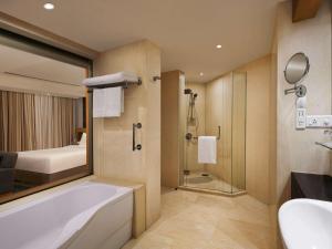 a bathroom with a tub and a bed and a shower at Novotel Hyderabad Convention Centre in Hyderabad