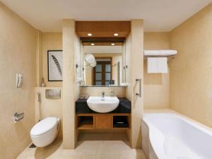 a bathroom with a sink and a tub and a toilet at Novotel Hyderabad Convention Centre in Hyderabad