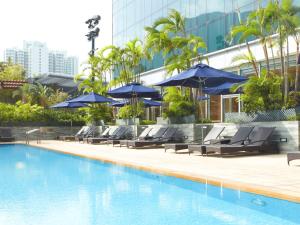 a swimming pool with lounge chairs and umbrellas at Novotel Citygate Hong Kong in Hong Kong