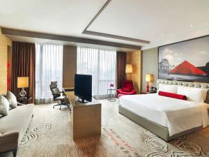 une chambre d'hôtel avec un grand lit et un salon dans l'établissement Sofitel Guangzhou Sunrich, à Canton