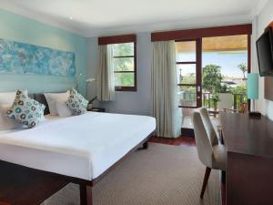 a bedroom with a large white bed and a balcony at Novotel Bali Nusa Dua in Nusa Dua
