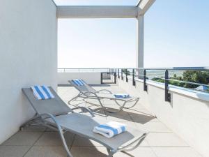 - deux chaises et des serviettes assises sur un balcon dans l'établissement Novotel Suites Nice Airport, à Nice