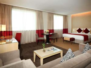 a hotel room with a bed and a living room at Novotel Riyadh Al Anoud in Riyadh