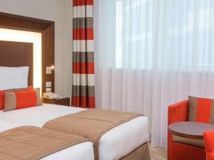 a hotel room with a bed and a chair at Novotel Dubai Al Barsha in Dubai