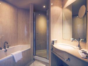 a bathroom with a shower and a tub and a sink at Mercure Cardiff Holland House Hotel & Spa in Cardiff