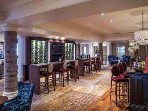 a living room with a bar and some chairs at Mercure Exeter Southgate Hotel in Exeter