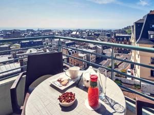 - une table avec un bol de nourriture et une bouteille sur le balcon dans l'établissement Mercure Granville Le Grand Large, à Granville