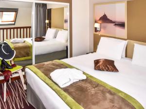a hotel room with two beds and a mirror at Mercure Granville Le Grand Large in Granville +37 photos