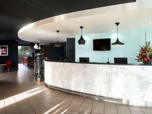 a lobby with a reception counter and pendant lights at ibis Swansea in Swansea