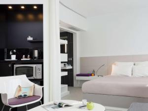 a bedroom with a bed and a table and chairs at Novotel Suites Malaga Centro in Málaga