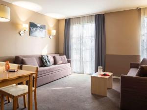 a living room filled with furniture and a window at Aparthotel Adagio Marne La Vallée - Val d'Europe in Serris