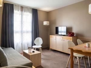 a living room filled with furniture and a tv at Aparthotel Adagio Marne La Vallée - Val d'Europe in Serris
